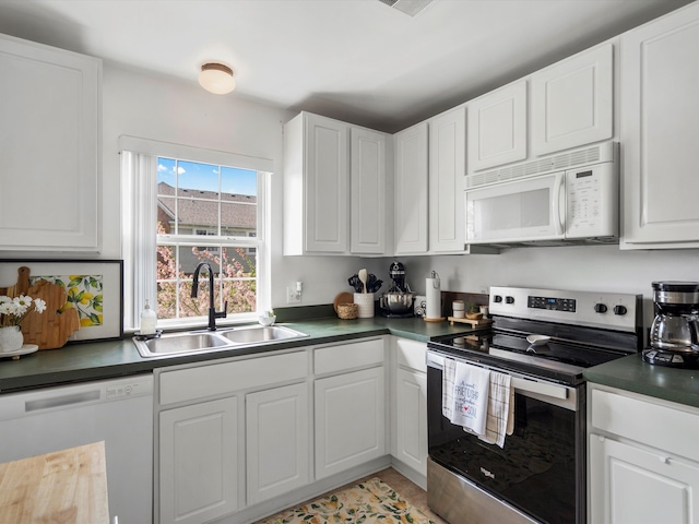 kitchen featuring a sink, white appliances, dark countertops, and white cabinets