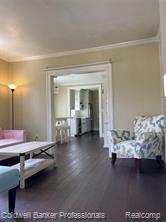 living area featuring wood finished floors and ornamental molding
