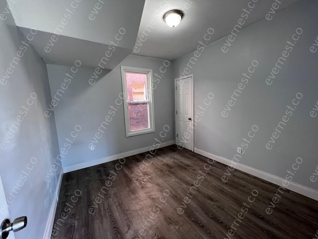 additional living space with baseboards and dark wood-type flooring