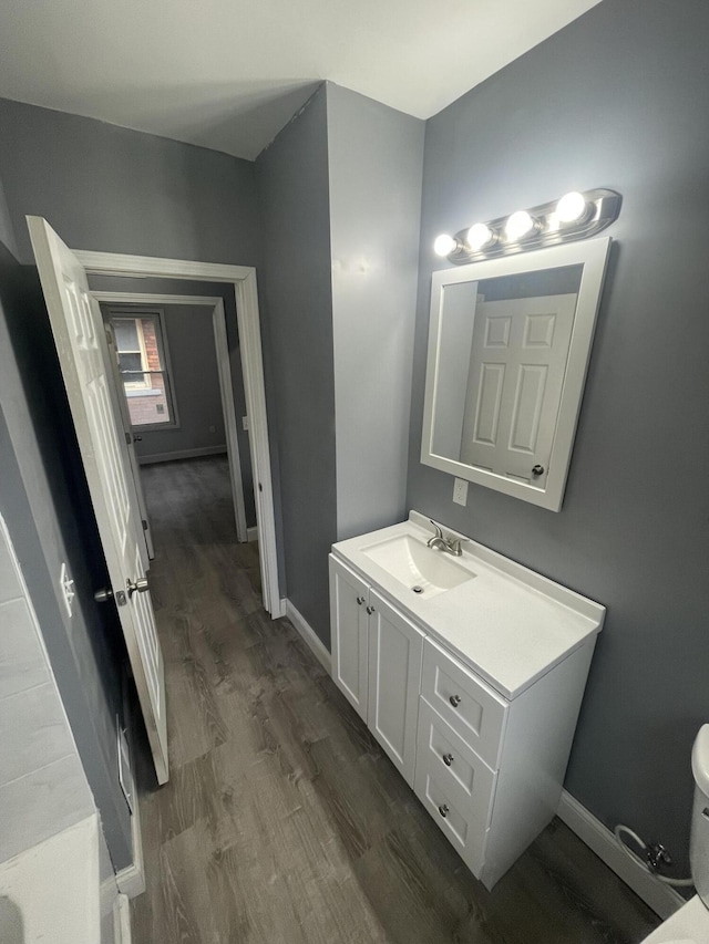 bathroom featuring vanity, toilet, baseboards, and wood finished floors