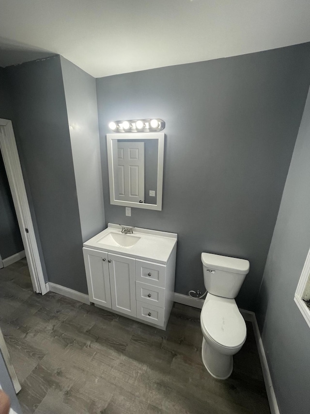 bathroom featuring vanity, toilet, wood finished floors, and baseboards