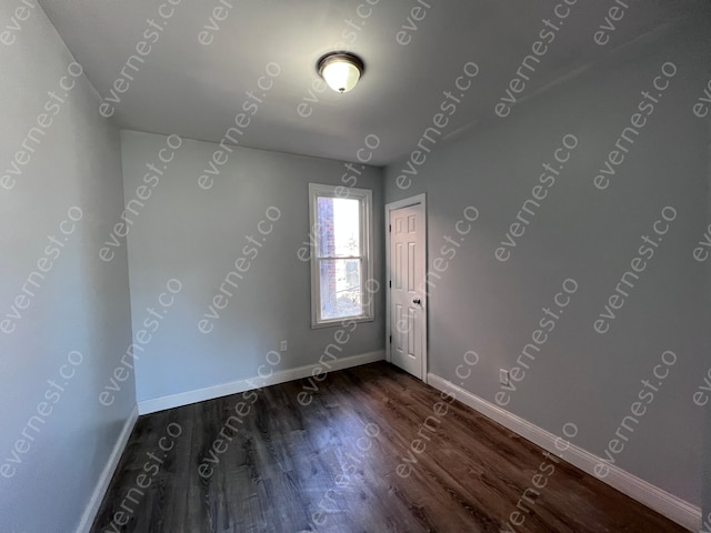 unfurnished room featuring dark wood-style flooring and baseboards