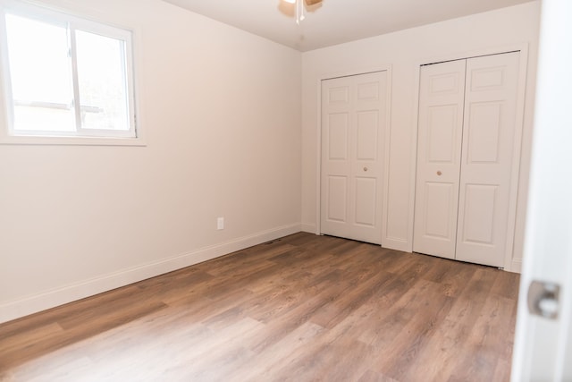 9114 Island Dr, Clay, MI 48001 - unfurnished bedroom with wood finished floors, baseboards, and two closets