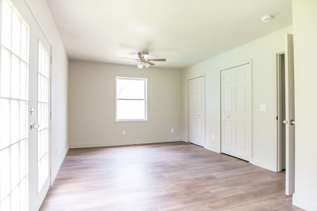 9114 Island Dr, Clay, MI 48001 - unfurnished bedroom featuring multiple closets, light wood-type flooring, baseboards, and a ceiling fan