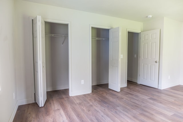 9114 Island Dr, Clay, MI 48001 - unfurnished bedroom featuring two closets, wood finished floors, and baseboards