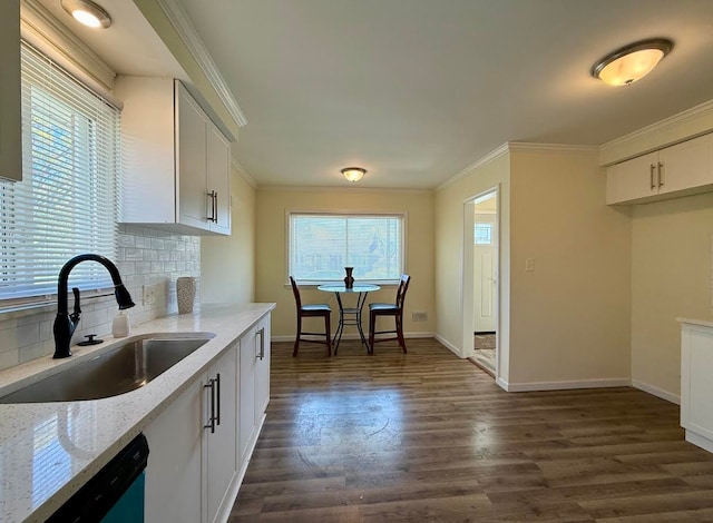 kitchen featuring a sink, dishwasher, backsplash, light stone countertops, and baseboards