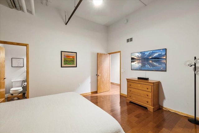 444 W Willis St Unit 204, Detroit, MI 48201 - bedroom featuring a high ceiling, wood finished floors, baseboards, and connected bathroom