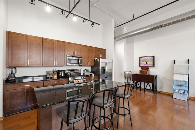 444 W Willis St Unit 204, Detroit, MI 48201 - kitchen with stainless steel appliances, a sink, track lighting, a towering ceiling, and dark wood-style floors