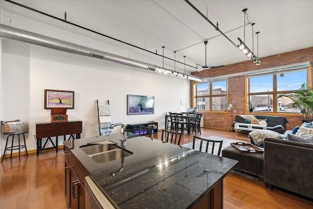 444 W Willis St Unit 204, Detroit, MI 48201 - kitchen with brick wall, a sink, open floor plan, wood finished floors, and a kitchen island with sink