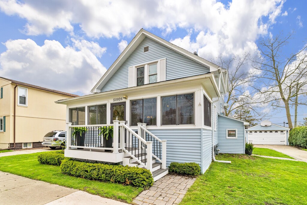bungalow with an outbuilding, a front yard, a sunroom, and a detached garage