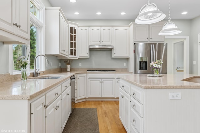 kitchen featuring under cabinet range hood, white cabinetry, appliances with stainless steel finishes, and a sink