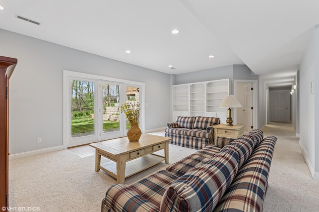 living area with baseboards, visible vents, and light colored carpet