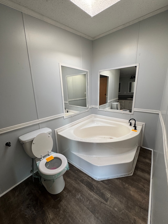 bathroom with a skylight, toilet, a textured ceiling, and wood finished floors