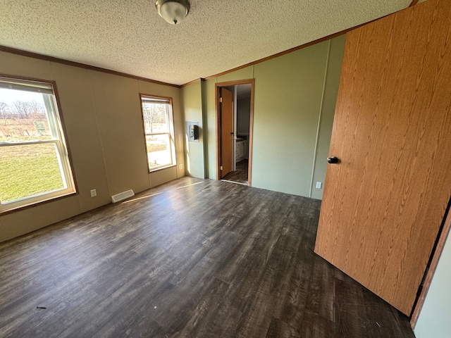 unfurnished room with ornamental molding, visible vents, a textured ceiling, and wood finished floors