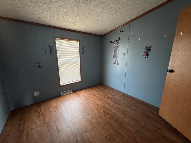 unfurnished room featuring a textured ceiling, visible vents, and wood finished floors