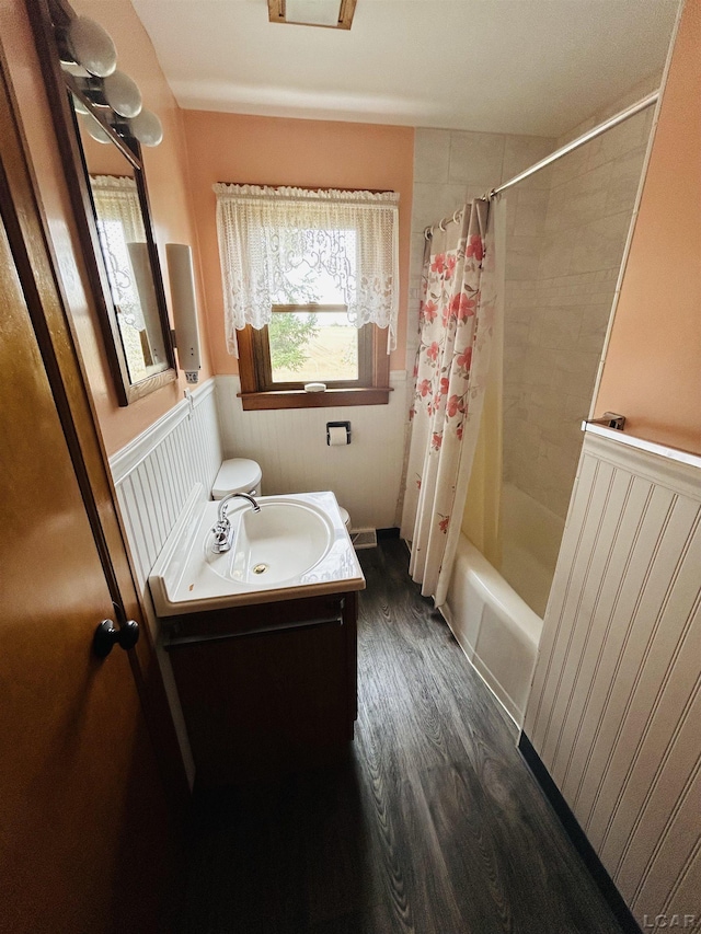 bathroom with wood finished floors, a wainscoted wall, visible vents, shower / bathtub combination with curtain, and vanity
