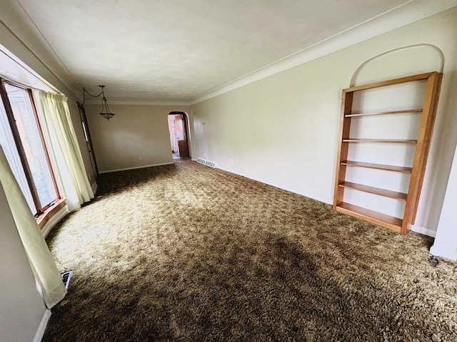 unfurnished living room with ornamental molding, carpet, arched walkways, and visible vents