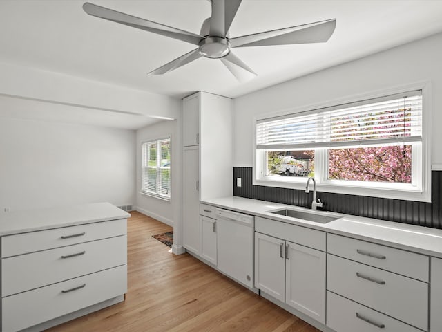 kitchen with a sink, dishwasher, light countertops, a ceiling fan, and light wood-style floors
