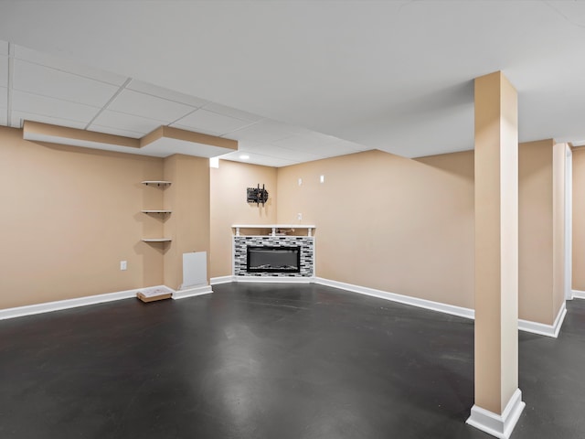 finished basement featuring a fireplace, baseboards, and a paneled ceiling