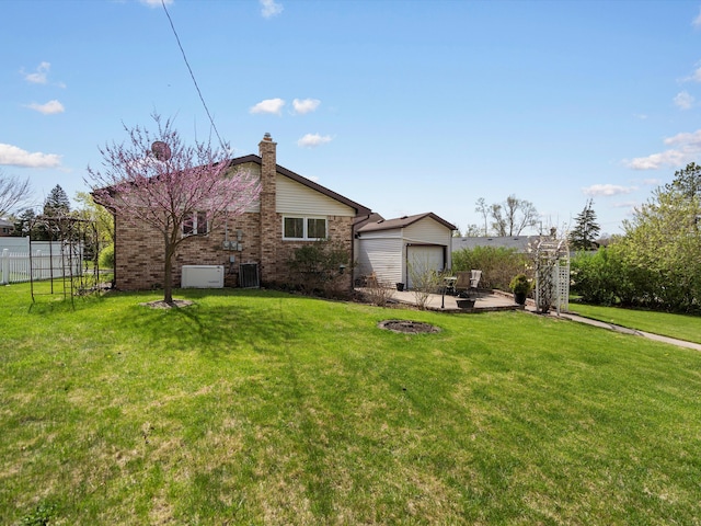 exterior space with fence, brick siding, a yard, a chimney, and central AC unit