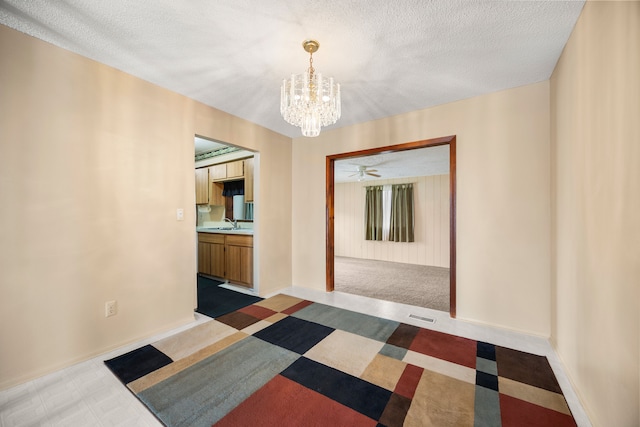 hallway with a sink, a chandelier, a textured ceiling, and visible vents
