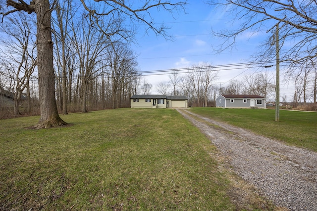 view of front of house with an attached garage, a front lawn, an outbuilding, and driveway
