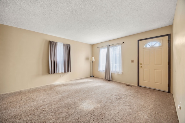 interior space featuring light colored carpet, a textured ceiling, and visible vents