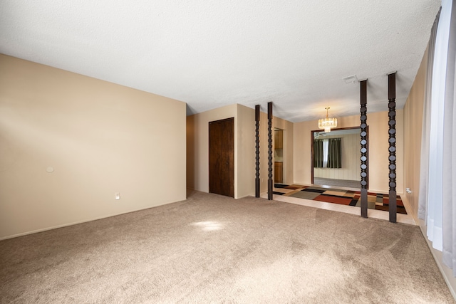 carpeted empty room featuring a textured ceiling and a chandelier