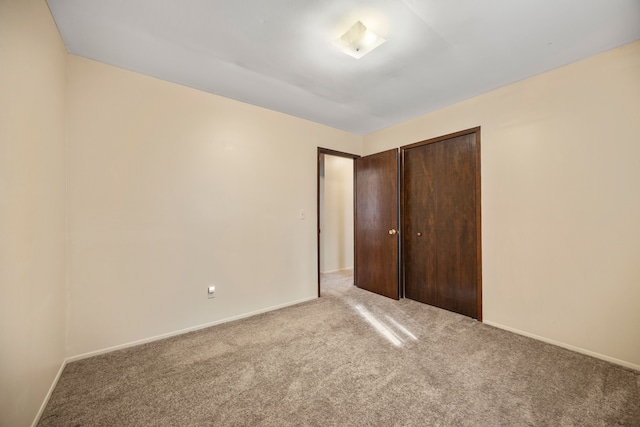unfurnished bedroom featuring carpet, a closet, and baseboards