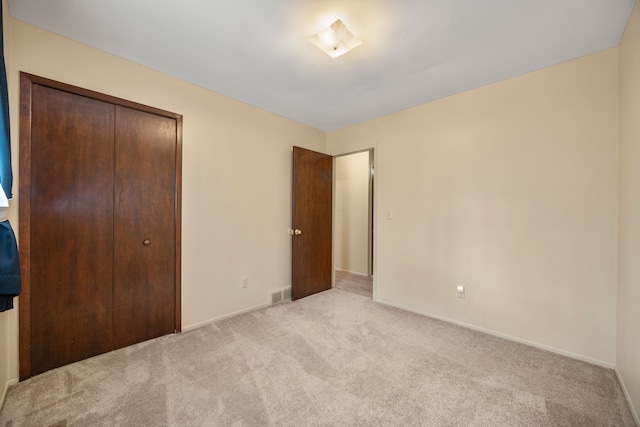 unfurnished bedroom featuring baseboards, a closet, visible vents, and carpet