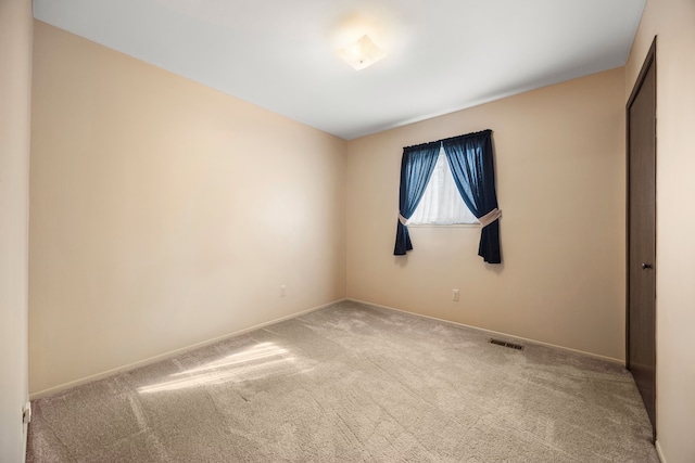 spare room featuring carpet flooring, visible vents, and baseboards
