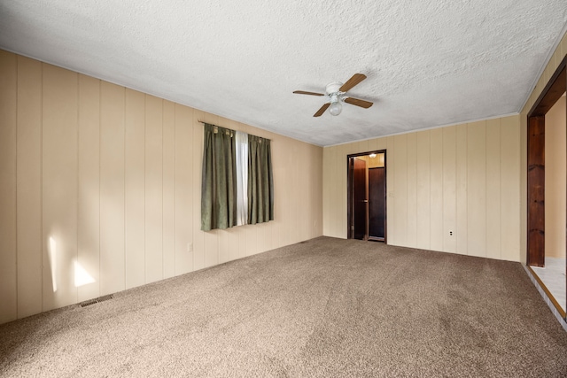carpeted empty room featuring a ceiling fan, visible vents, and a textured ceiling