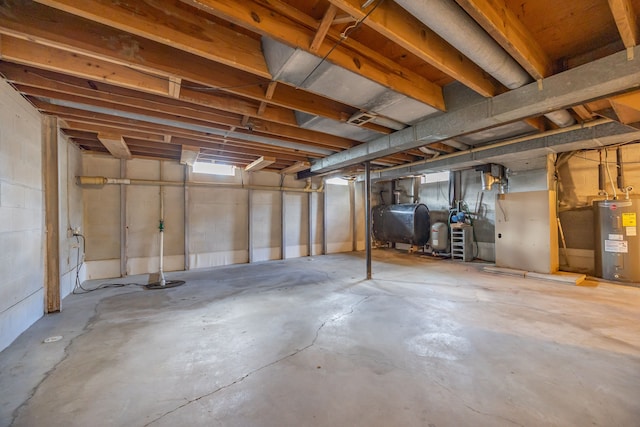 unfinished below grade area with electric water heater, heating fuel, and heating unit