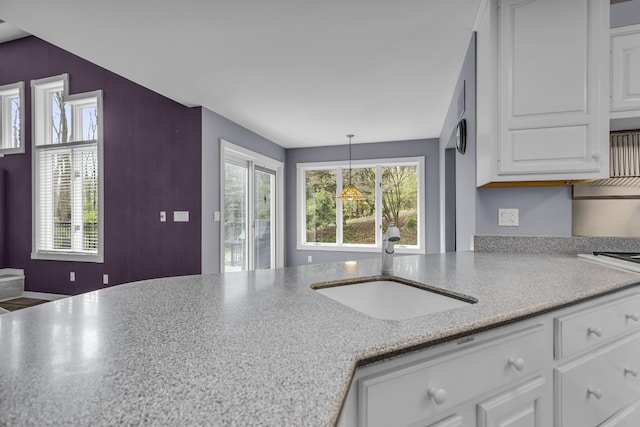 kitchen with decorative light fixtures, white cabinetry, and a sink