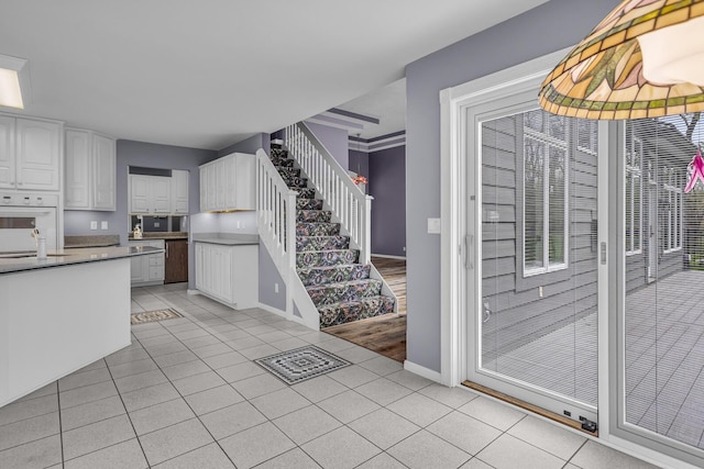 interior space featuring light tile patterned floors, baseboards, white cabinets, and oven