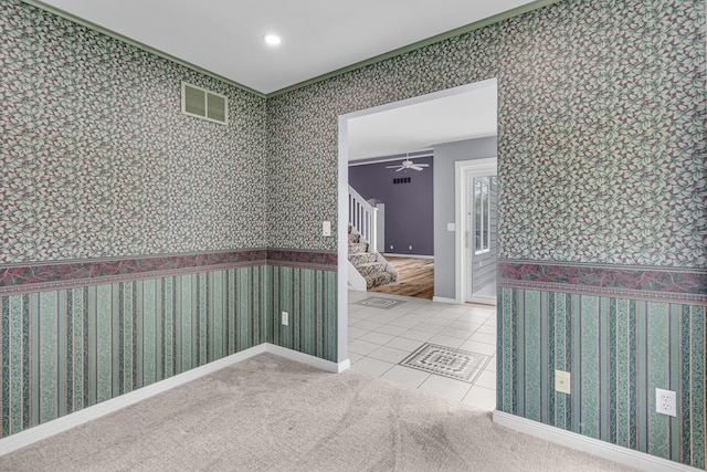 tiled spare room with wallpapered walls, ornamental molding, ceiling fan, visible vents, and stairway