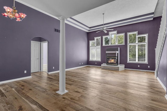 unfurnished living room with arched walkways, a glass covered fireplace, ceiling fan, and wood finished floors