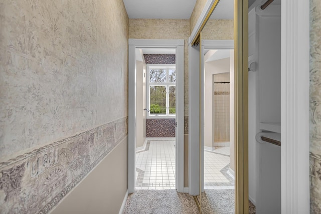 hallway featuring wallpapered walls and baseboards