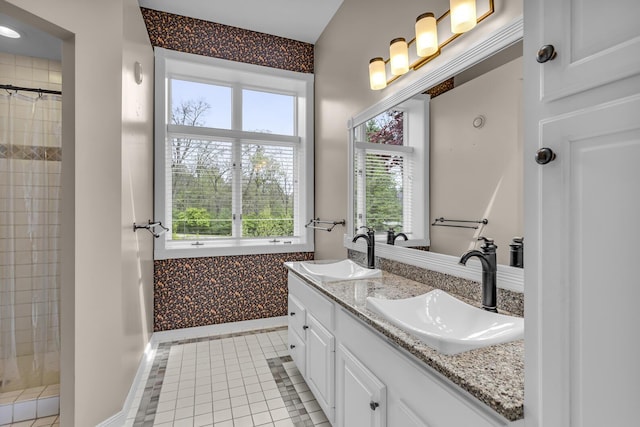 full bath featuring a tile shower, plenty of natural light, and a sink
