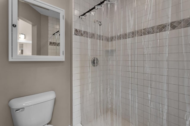 bathroom featuring toilet and a shower stall