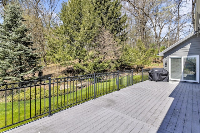 wooden deck with a grill and a lawn