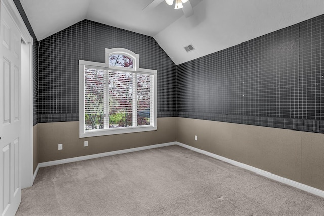 empty room with ceiling fan, lofted ceiling, carpet, and visible vents