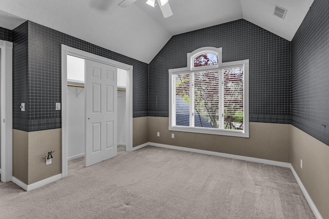 unfurnished bedroom with carpet flooring, a ceiling fan, a closet, visible vents, and vaulted ceiling