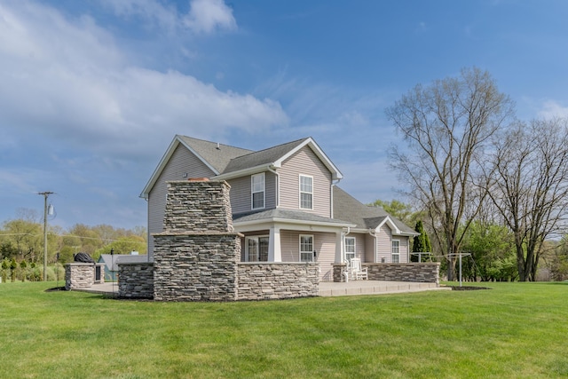 back of property featuring a yard, stone siding, and roof with shingles