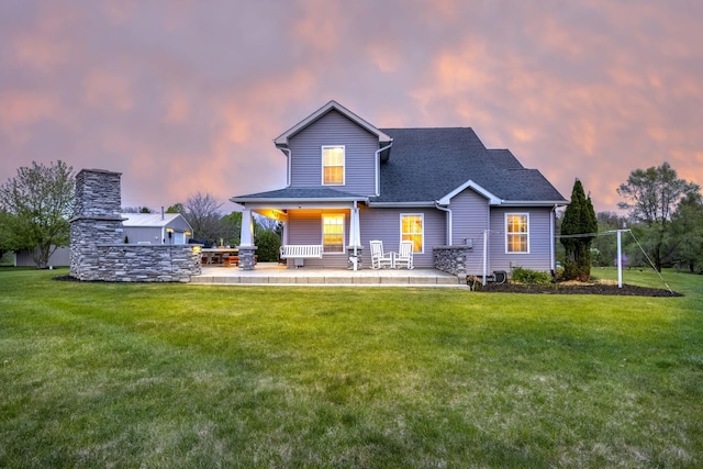 view of front of house featuring a shingled roof and a lawn