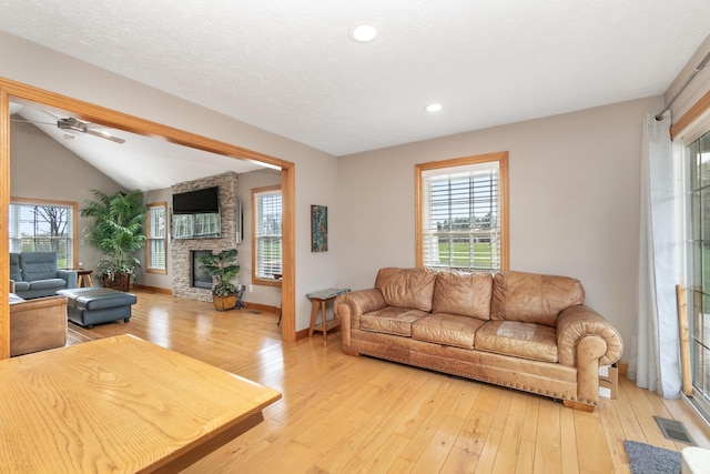 living area featuring light wood finished floors, a fireplace, and a healthy amount of sunlight
