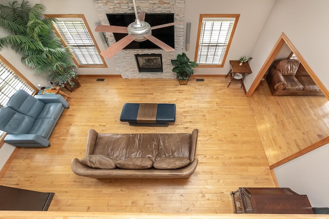 living area with baseboards, visible vents, a fireplace, and wood-type flooring