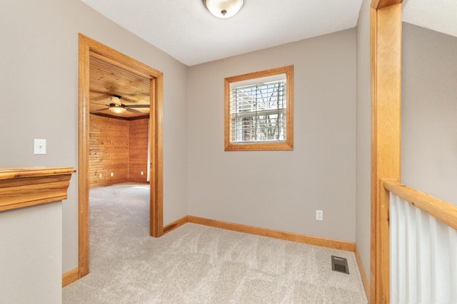interior space featuring light colored carpet, baseboards, ceiling fan, and visible vents