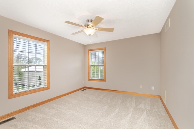 empty room with baseboards, visible vents, and light colored carpet