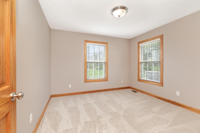 carpeted spare room featuring baseboards and visible vents